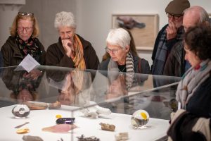 Three women looking into a cabinet of small sculptures by Kiki Smith at Modern Art Oxford