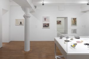 Installation photograph of Kiki Smith: I am a Wanderer at Modern Art Oxford featuring several photographs of sculpture and the side of a cabinet containing small sculptures