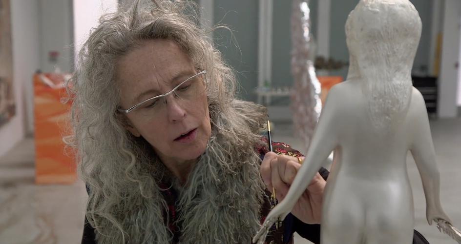 Kiki Smith painting a sculpture of a human figure